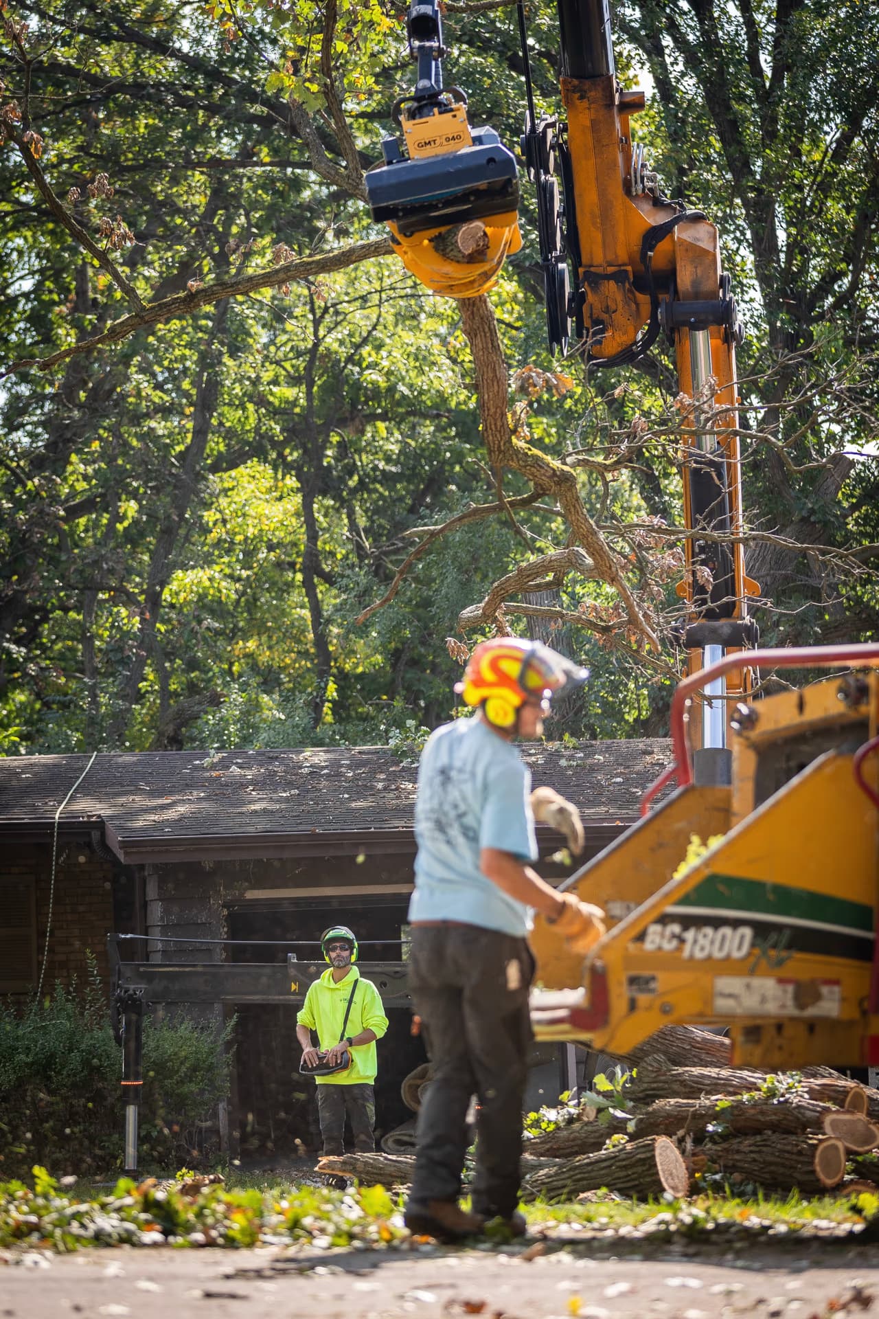 Arborist chipping brush beside a home on a village lot