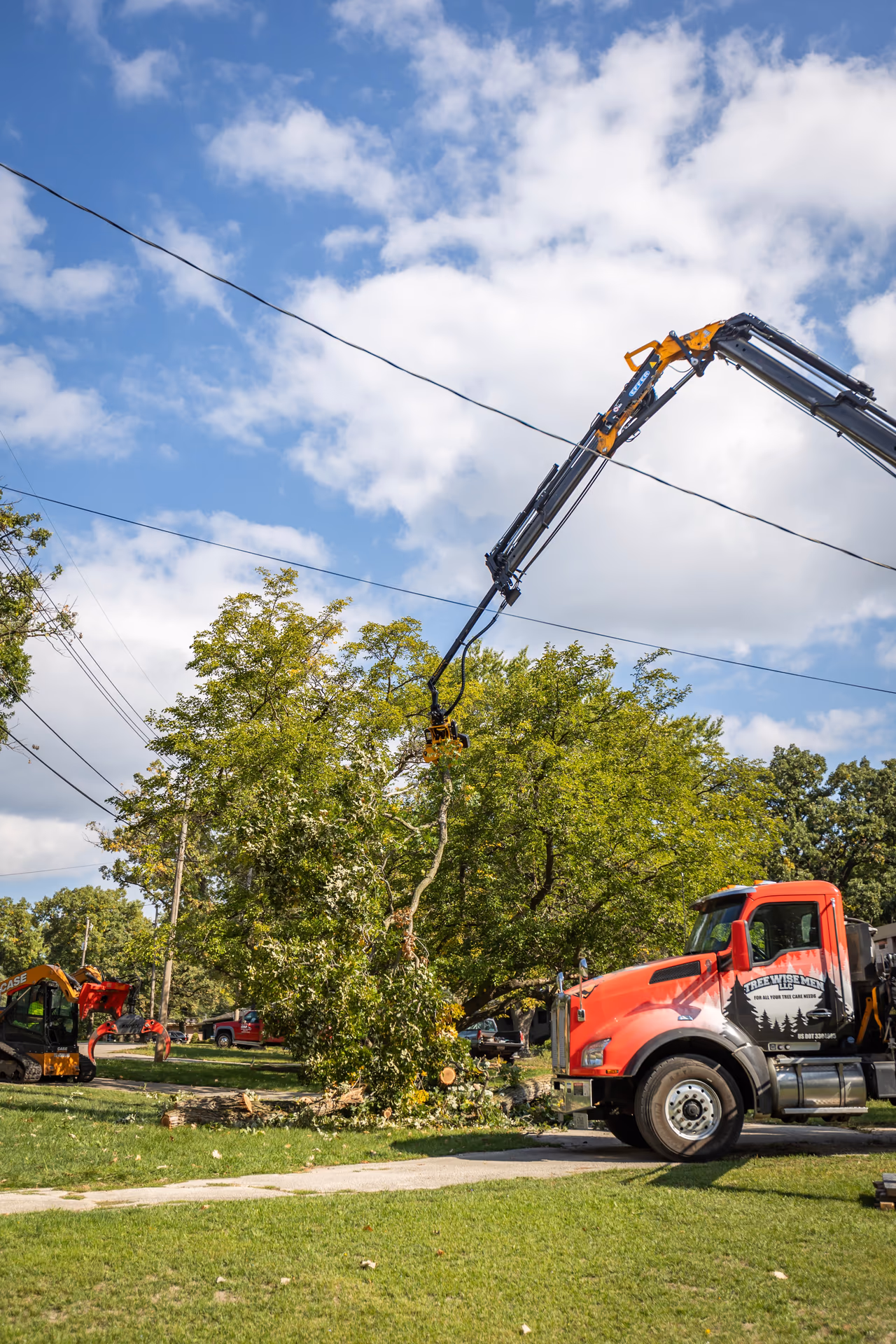 Boom truck reaching over utility lines during a tree removal in Southern Wisconsin