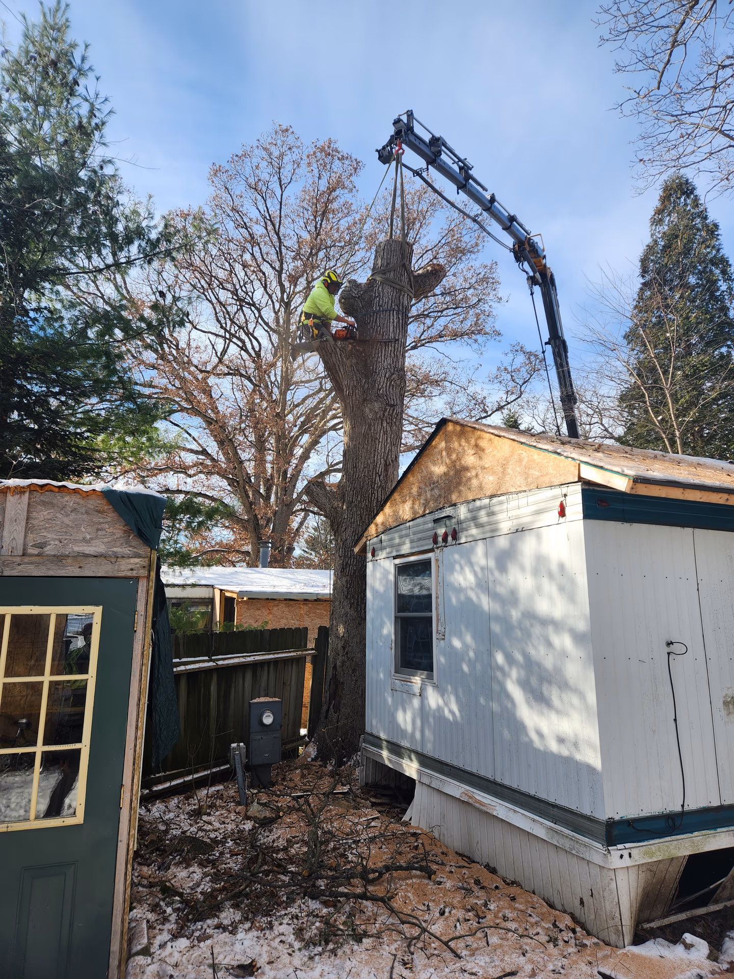 Crane-assisted trunk removal over a home during emergency response