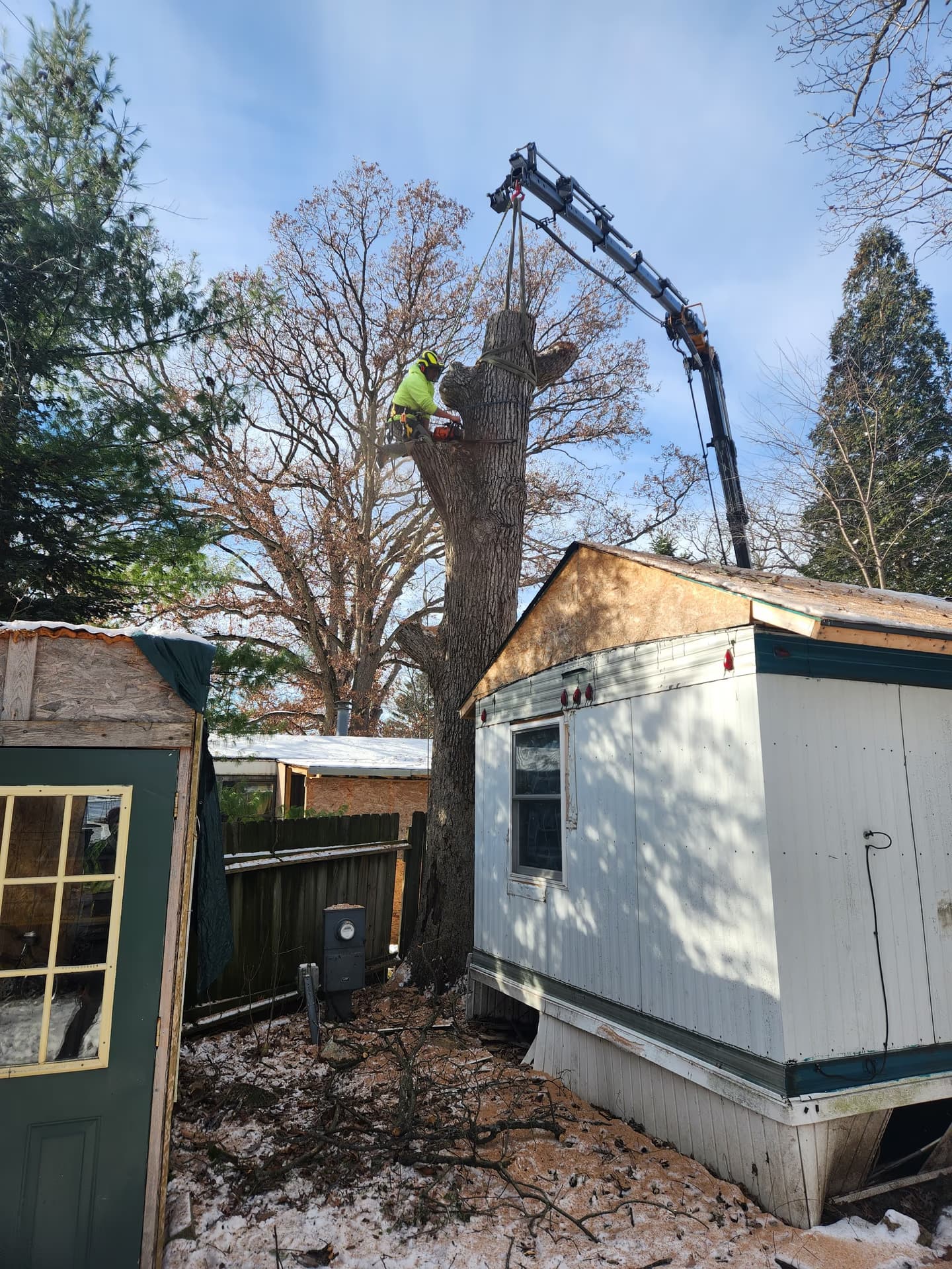 Crane-assisted trunk removal over a home during emergency response