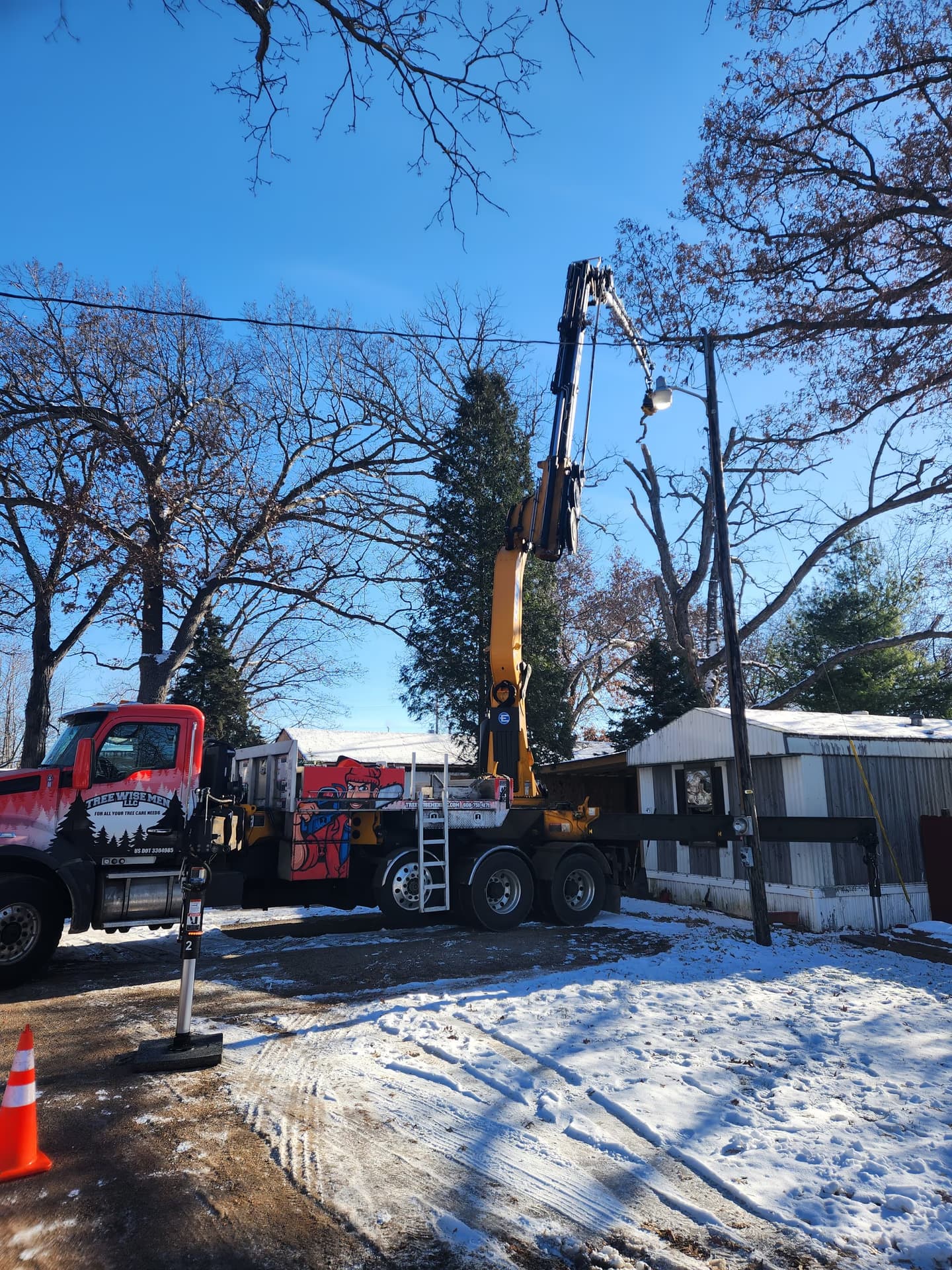 Crane Boom Over a Dead Oak Beside a Mobile Home