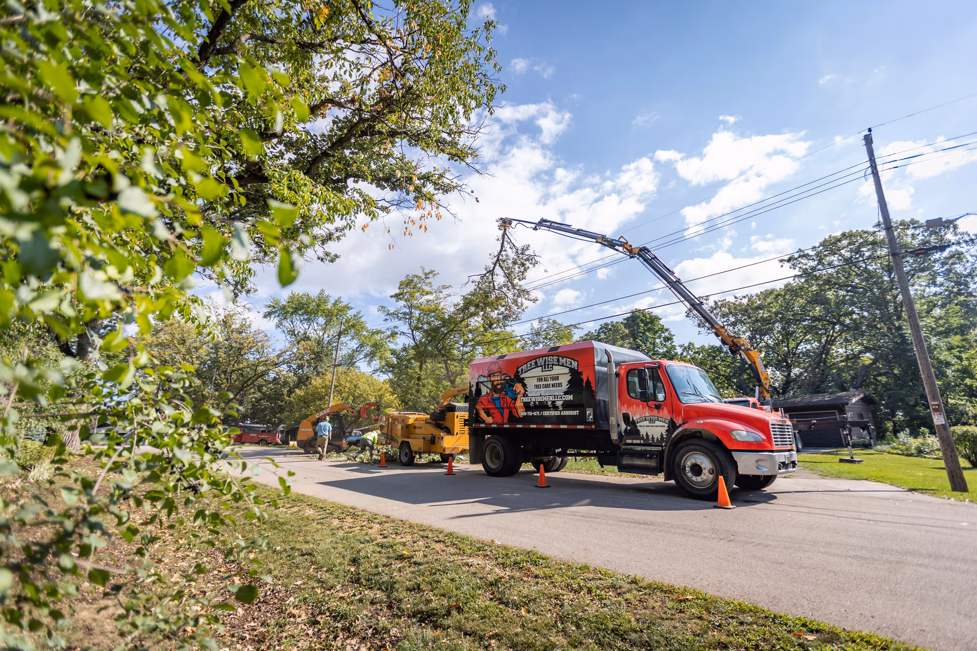 Tree Wise Men crane lifting a cut tree section clear of a Southern Wisconsin home