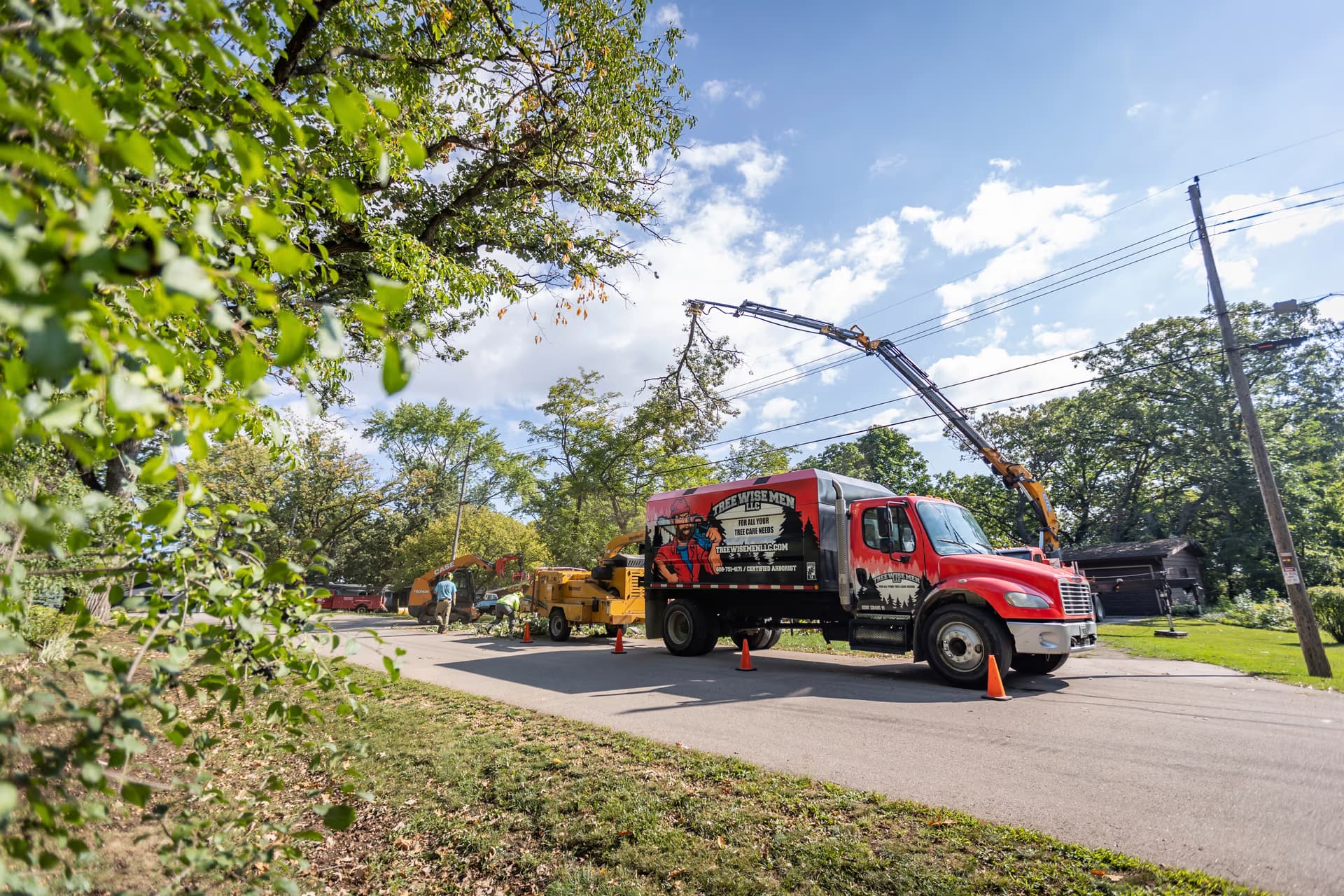 Tree Wise Men crane lifting a cut tree section clear of a Southern Wisconsin home