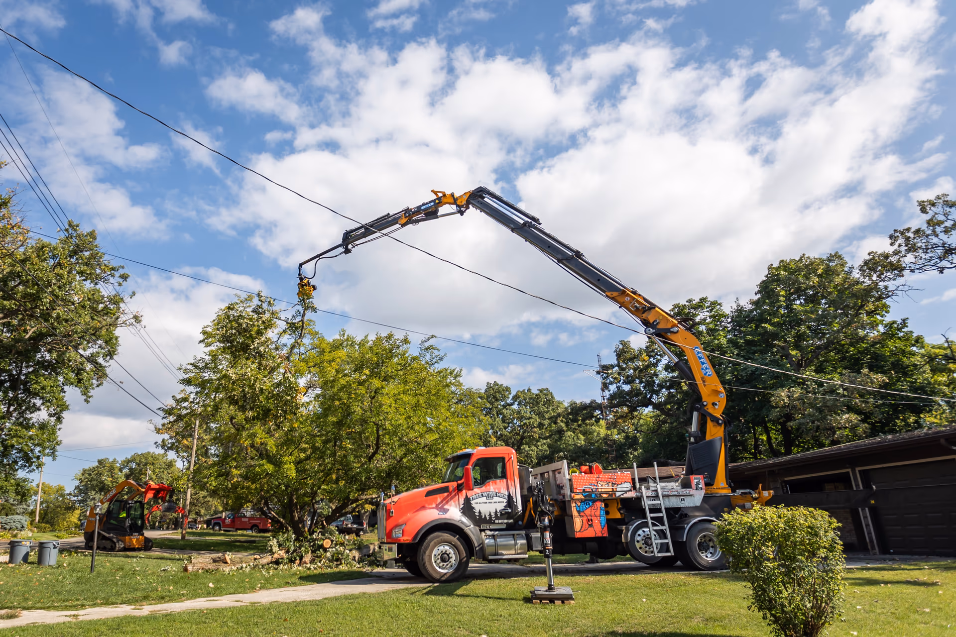 Crane truck with outriggers set on ground mats for a residential tree removal