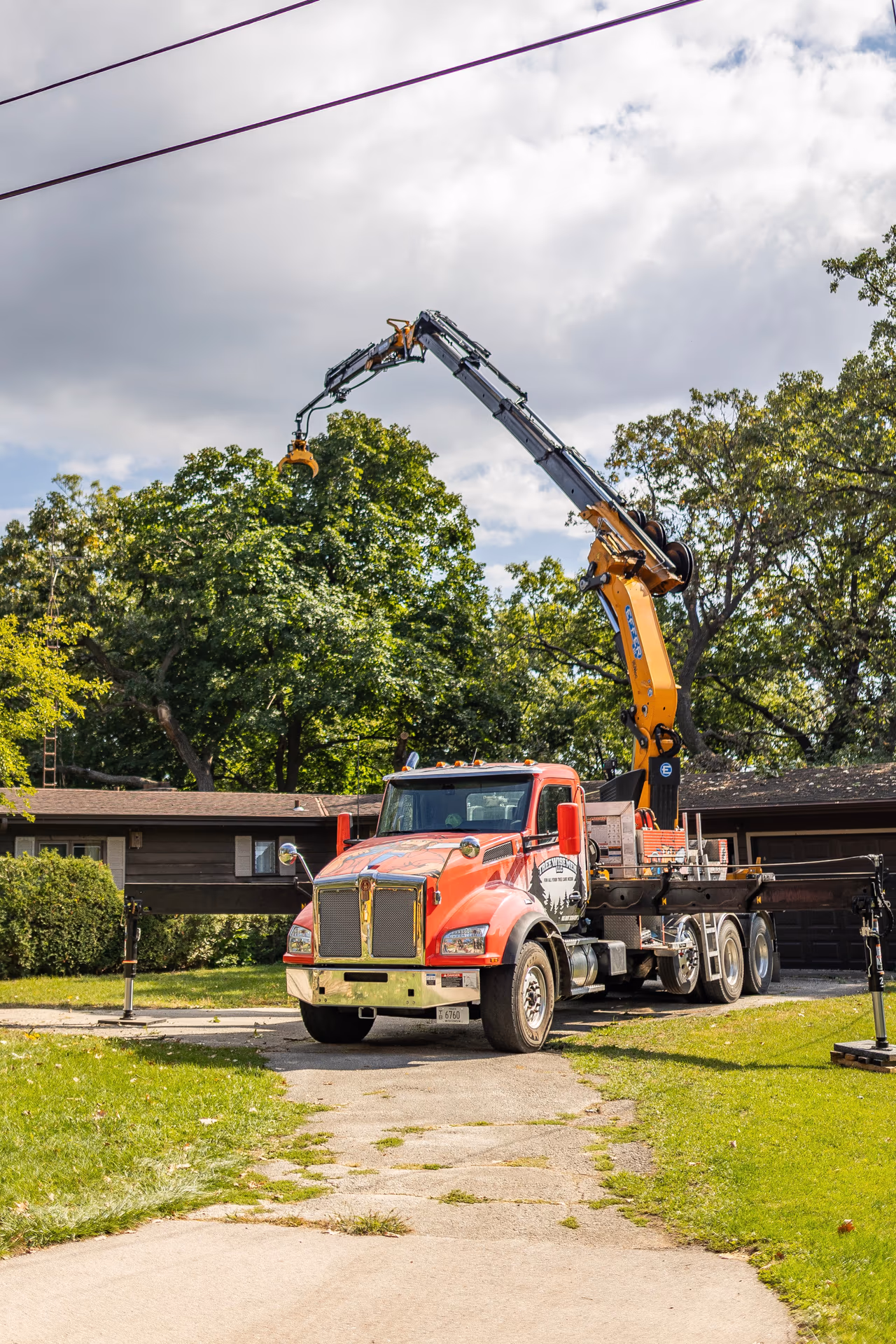 Crane truck positioned in a driveway for a residential tree removal