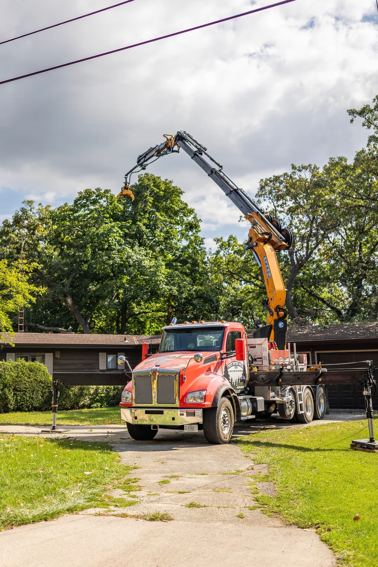 Crane truck positioned in a driveway for a tight-access tree removal