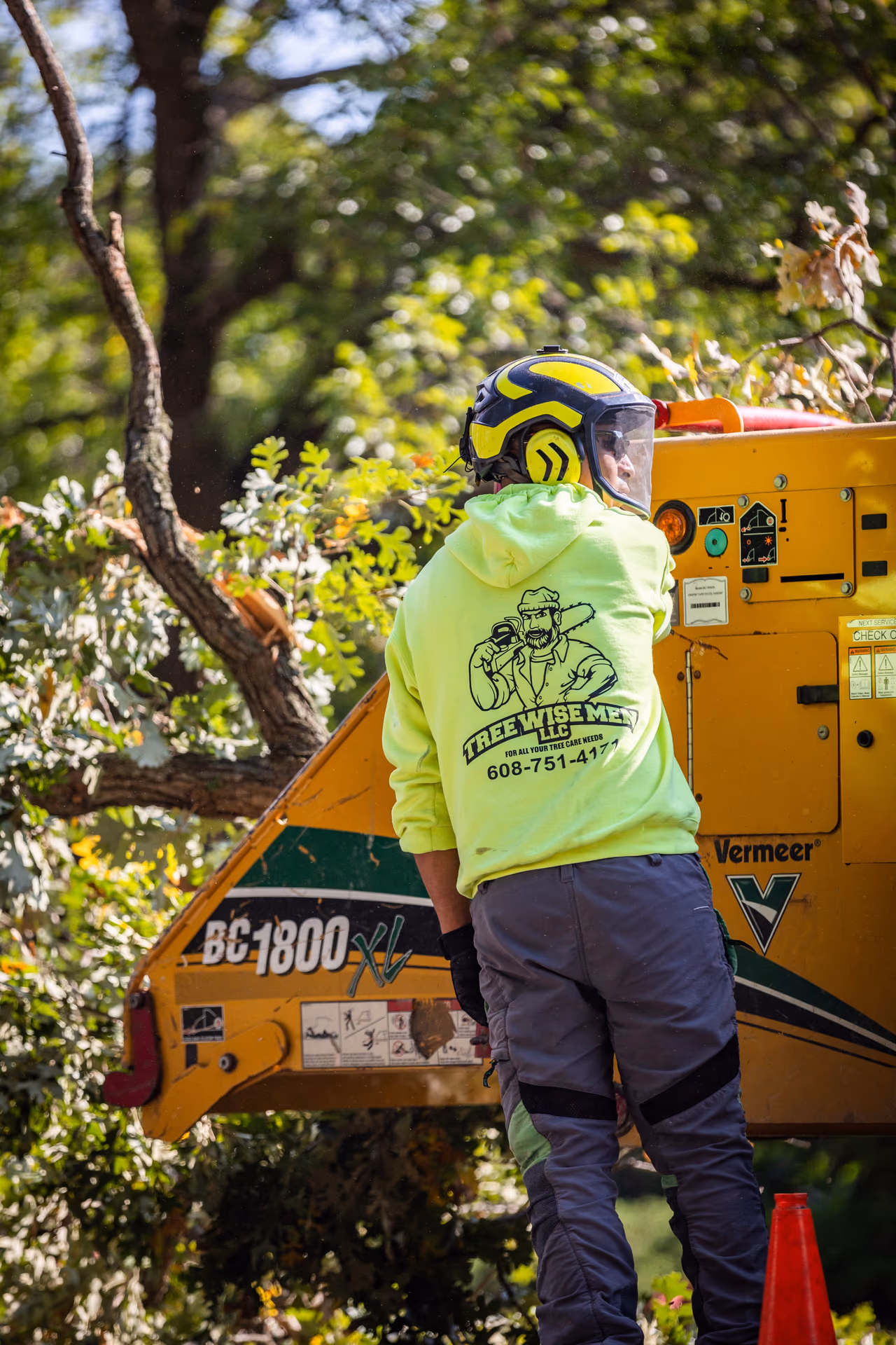 Tree Wise Men crew member in branded gear working a chipper