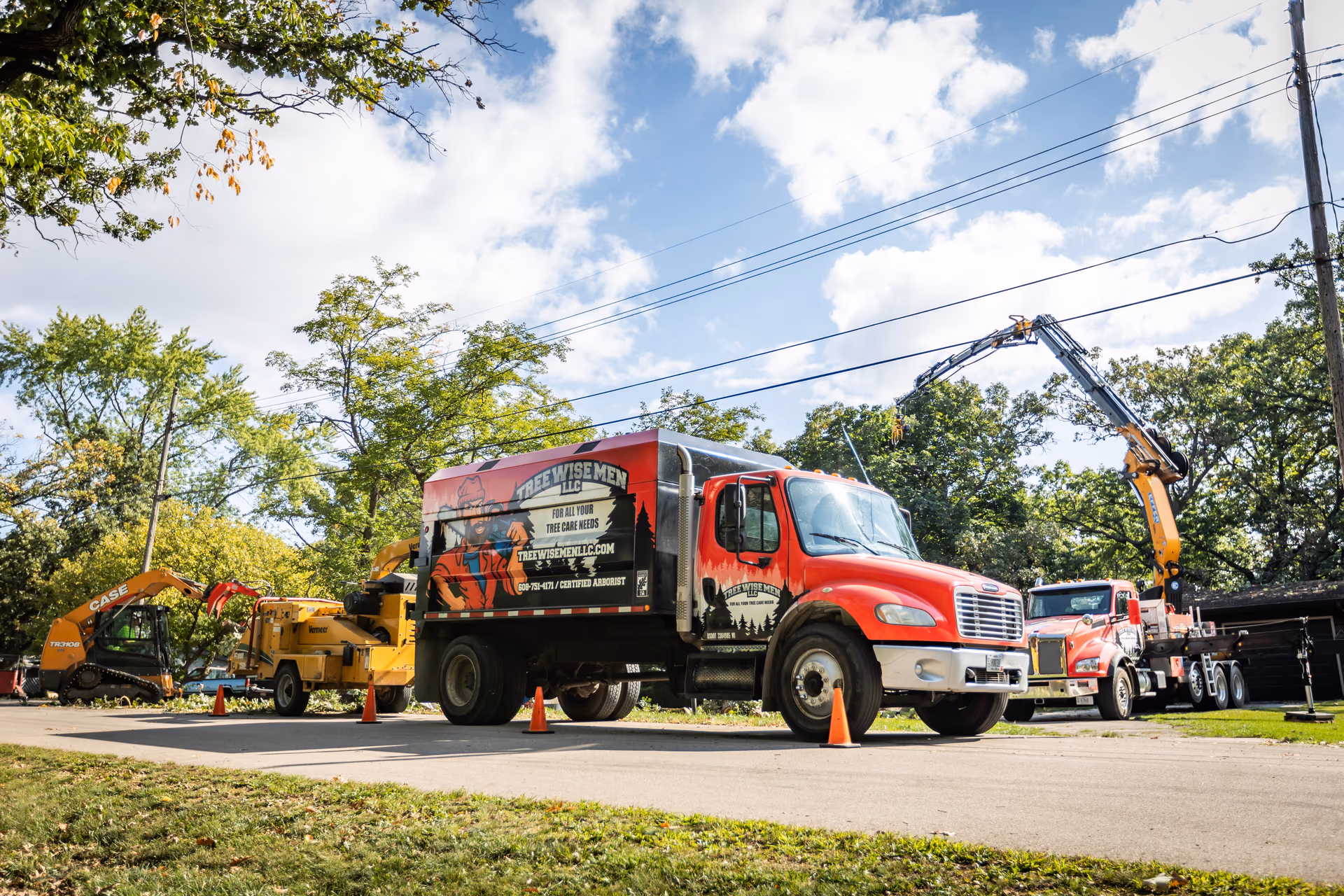 Tree Wise Men truck fleet and chipper staged on a community tree-care job